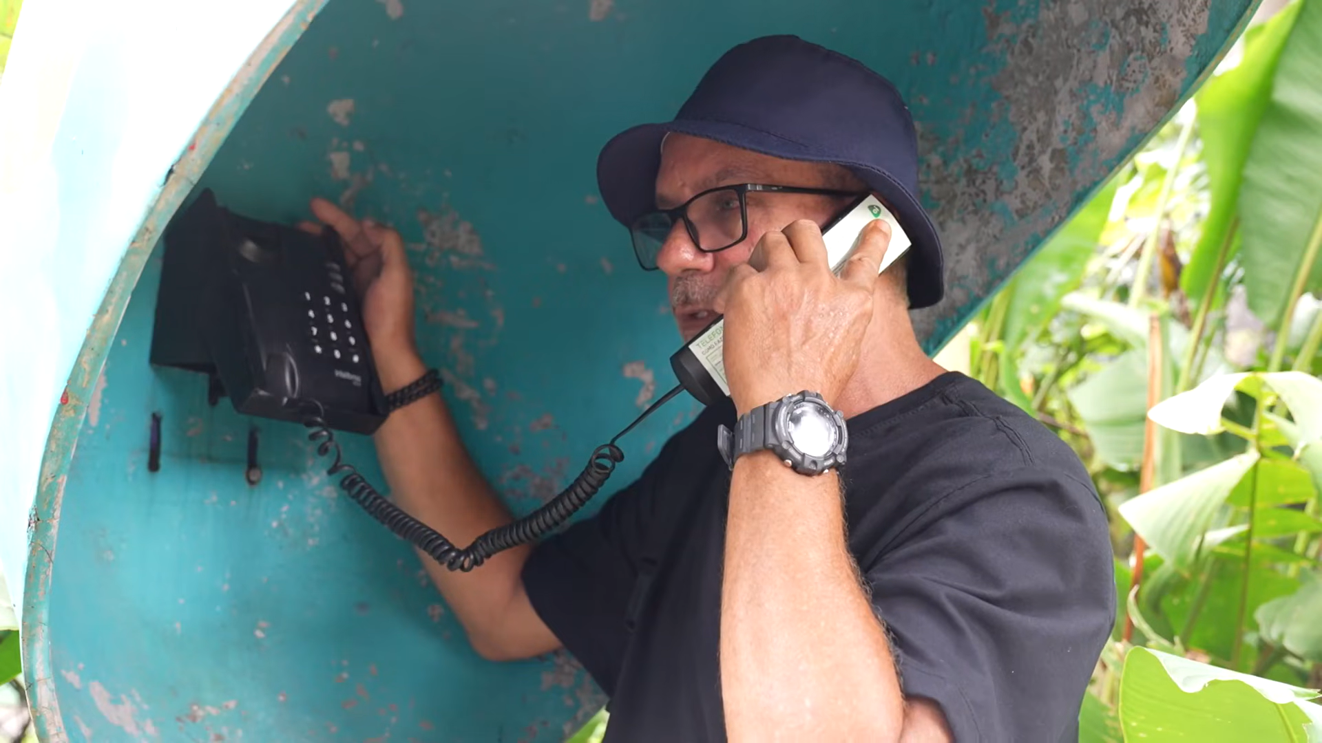 Morador Ed atendendo o telefone público durante a reportagem